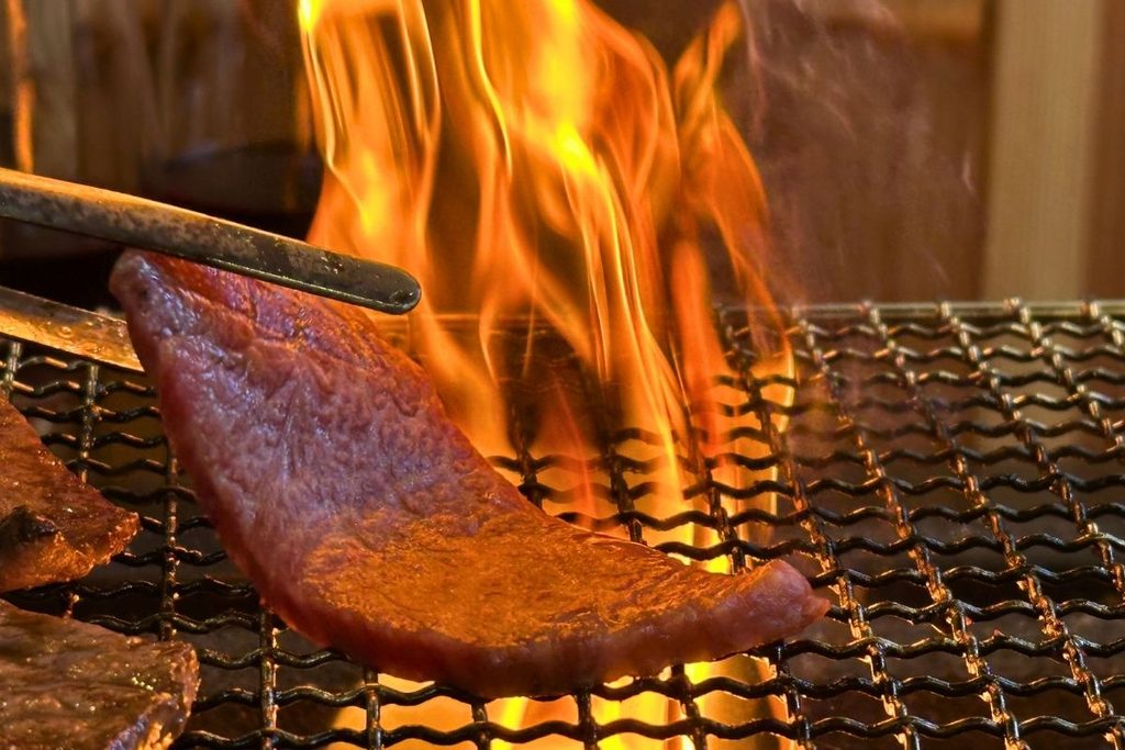 Beef grilling over open charcoal flames
